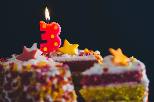 birthday cake with a burning candle on top in the shape of a 3
